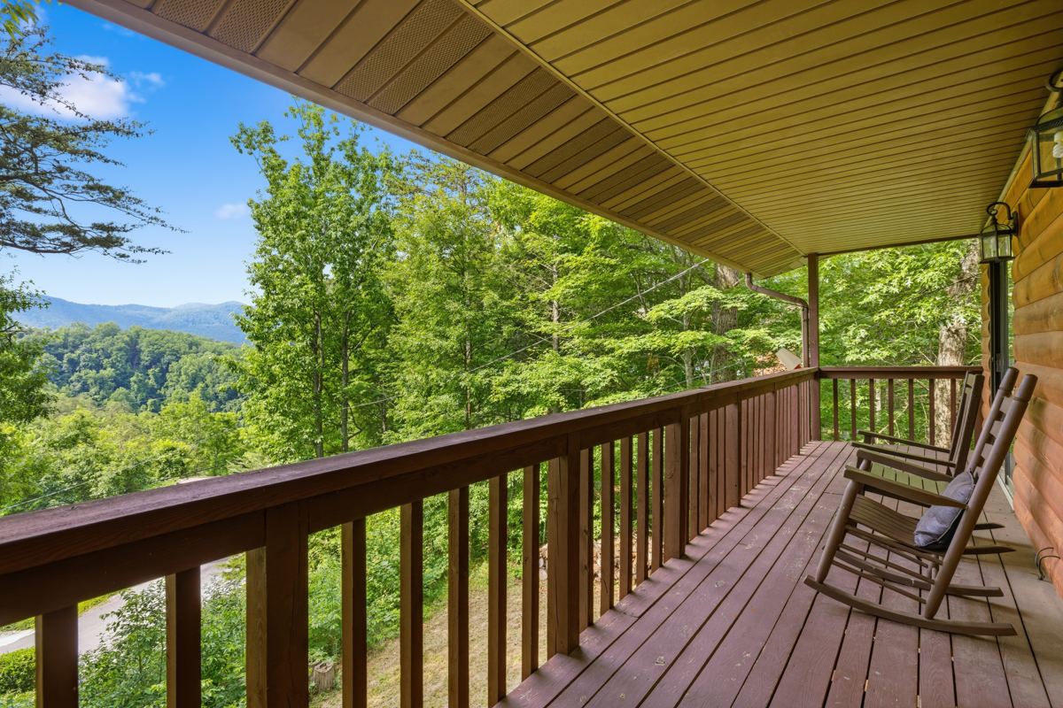 Covered balcony with rocking chairs looking out over green ridges